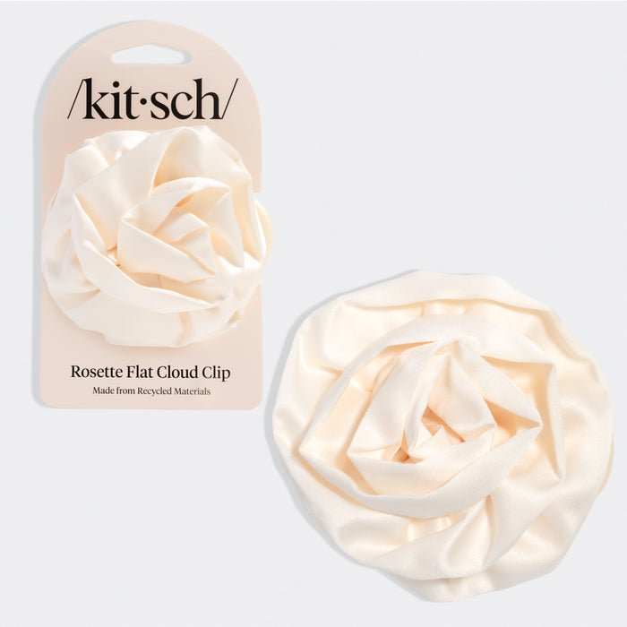 Cream-colored hair clip shaped like a soft rosette with layered, cloud-like petals. Shown next to beige packaging labeled “Kitsch” and “Rosette Flat Cloud Clip – Made from Recycled Materials.”